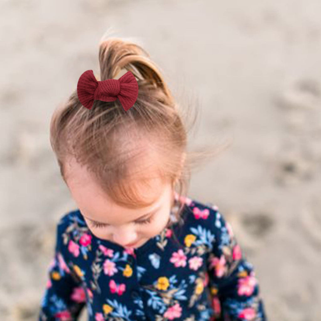 Child with a red bow in their hair wearing a floral dress on a blurred background