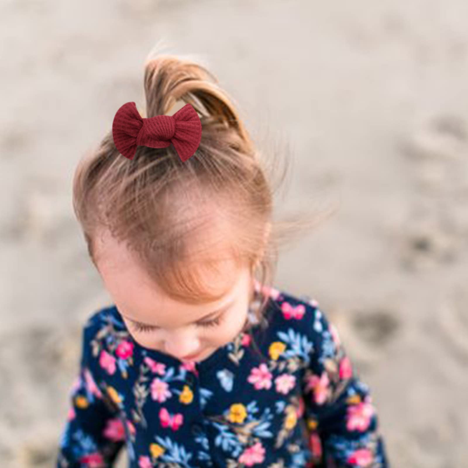 Child with a red bow in their hair wearing a floral dress on a blurred background